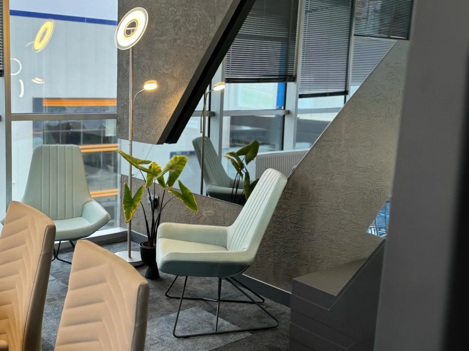 Office interior — a reception lounge with upholstered chairs beside an angular staircase